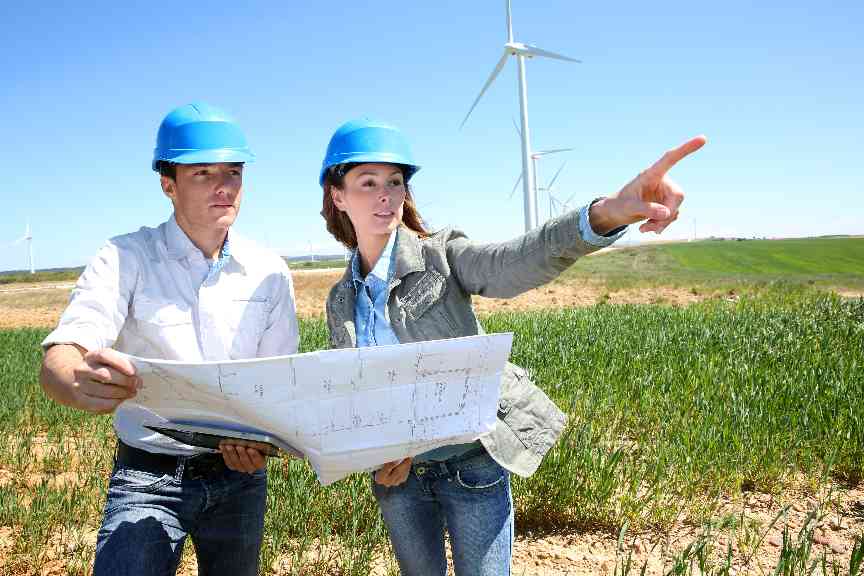 Zwei Personen mit Schutzhelm und Projektplan diskutieren über Windenergieanlagen.